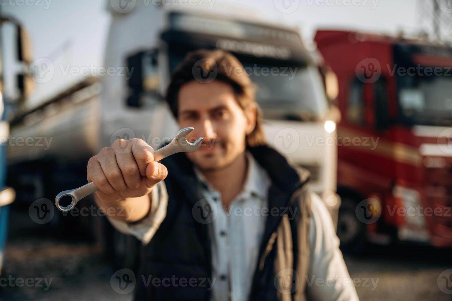 Tool in hand. Truck ,,driver, is near the transport outdoors photo