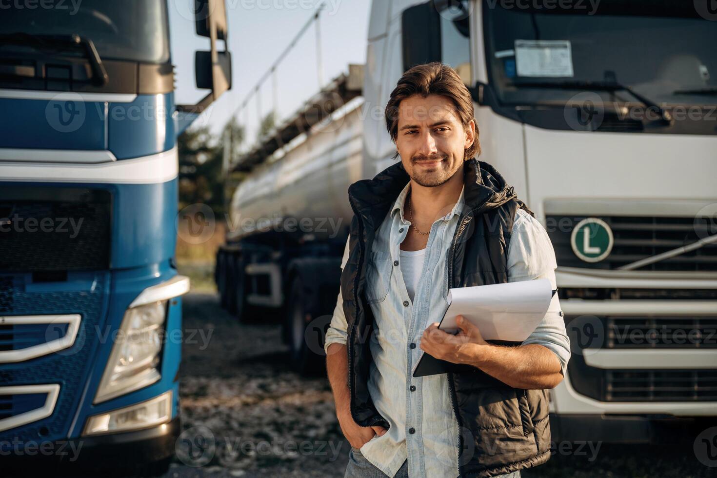 Black notepad, ,,standing and holding it. Truck driver is near the transport outdoors photo