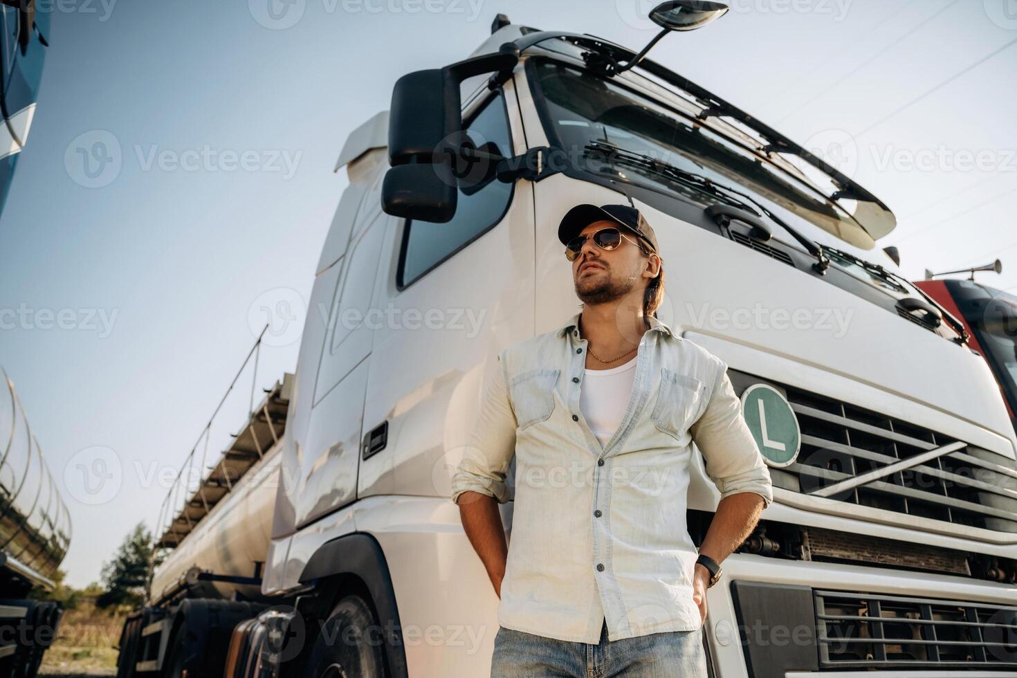 View, from, below, standing ,and ,posing. Truck driver is near the transport outdoors photo