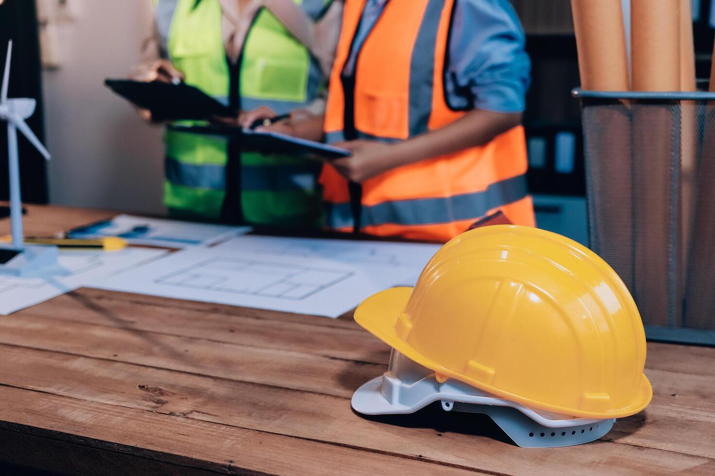 Two women in hard hats and vests standing next to a table with construction plans photo