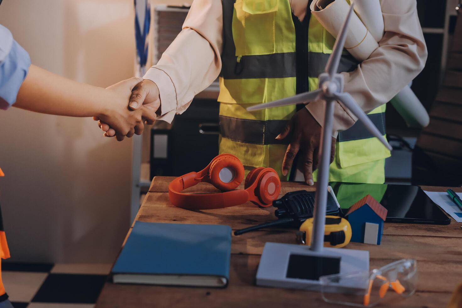 Two people shaking hands at a table with construction tools photo