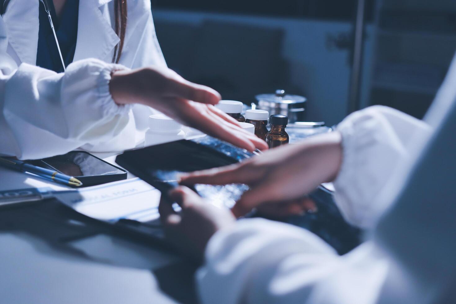 A doctor is holding a tablet computer while another person is sitting at a desk photo
