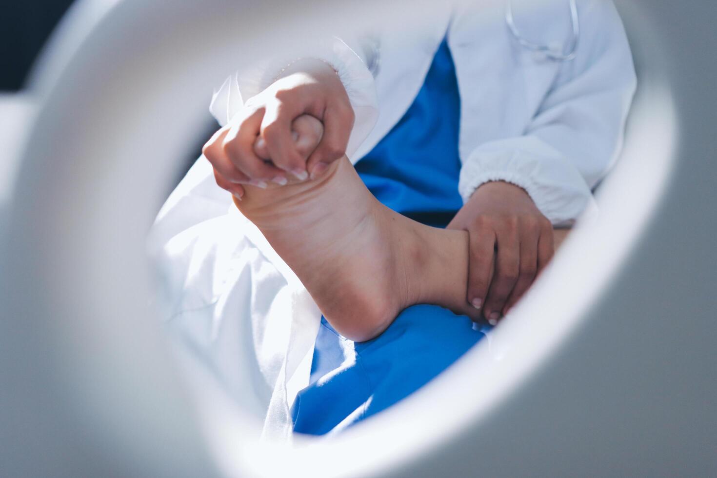 A person in a blue robe is holding their foot photo