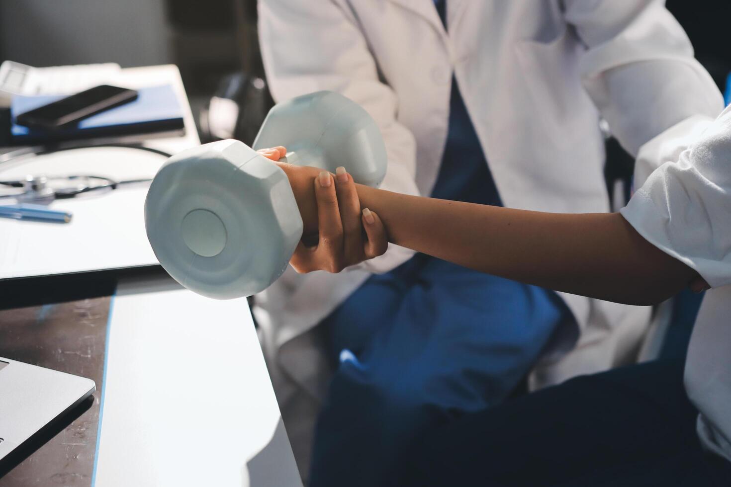 A doctor is holding a dumbbell while a woman is sitting at a desk photo