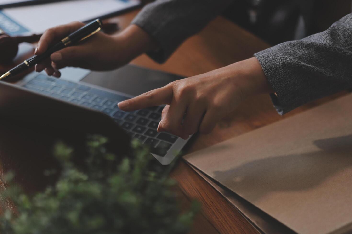 A person is using a pen and pointing at a laptop photo