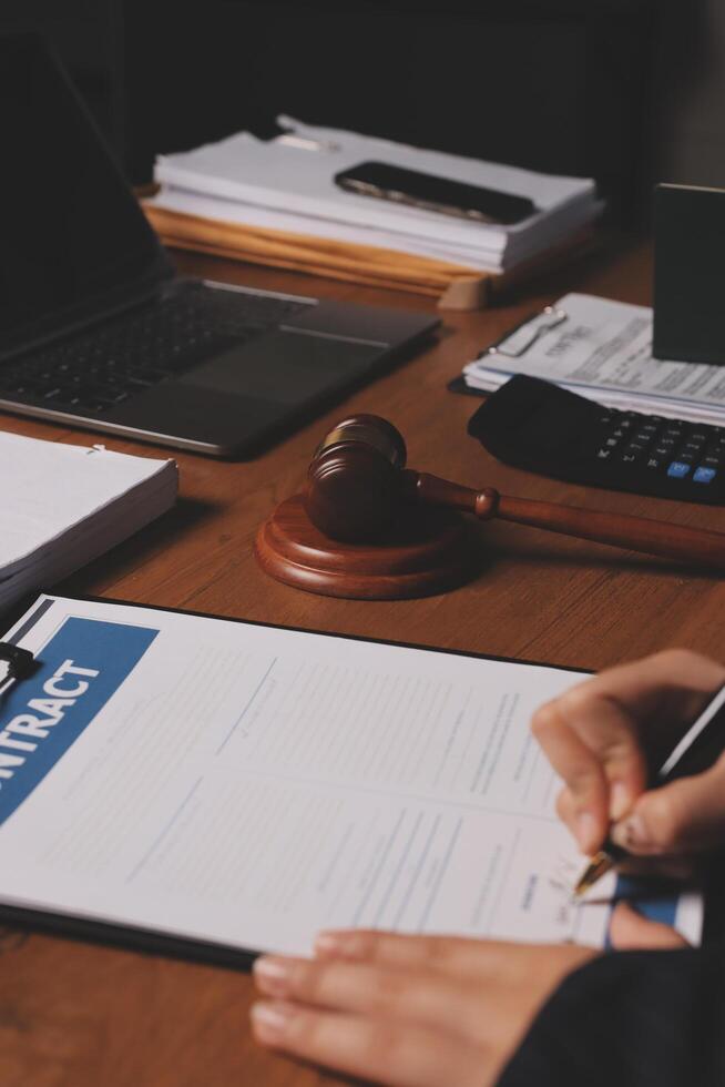 A person signing a contract on a desk with a gavel photo