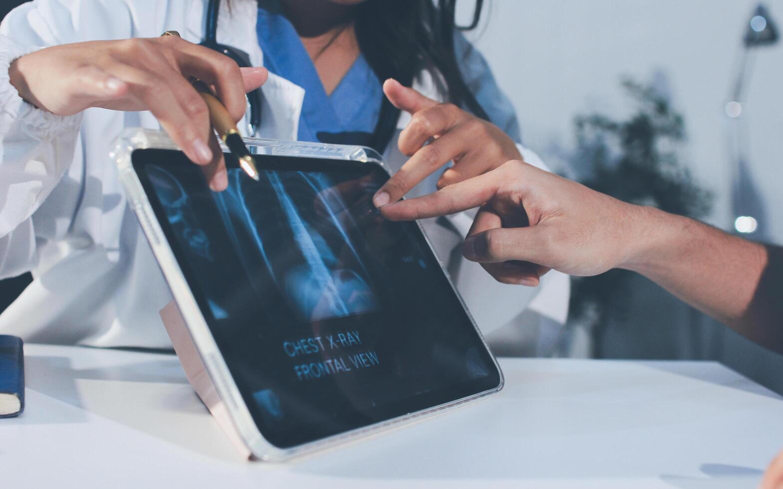 A doctor is using an ipad to show a patient an x - ray photo
