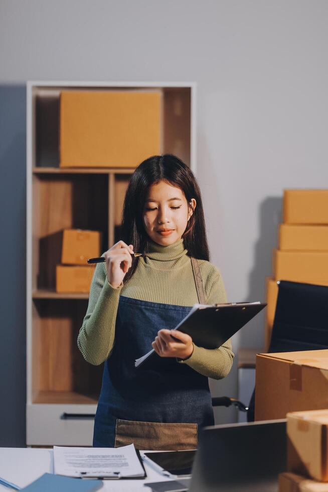 A woman is standing in front of boxes and holding a clipboard photo
