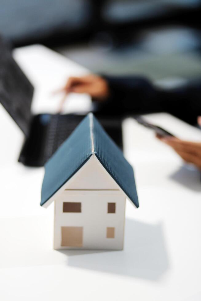 A woman using a laptop and a house model on a table photo