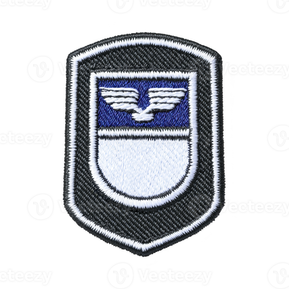 This shows black and white embroidered patch with shield design featuring winged emblem. patch has blue section at top and white section below, bordered by black outline png