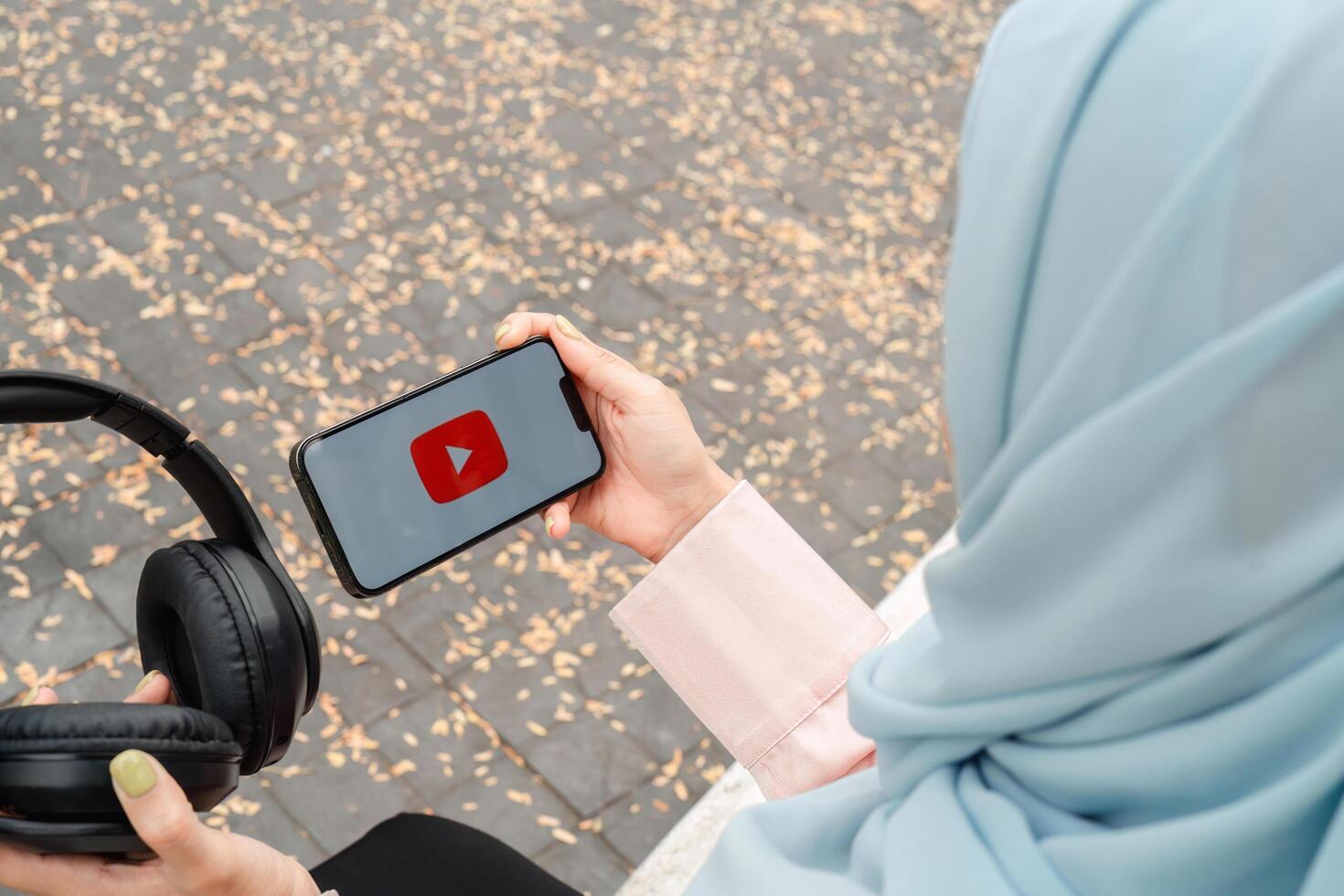 CHIANG MAI ,THAILAND JAN 2025 . Woman holding a iPhone 14 with social Internet service Youtube on the screen photo