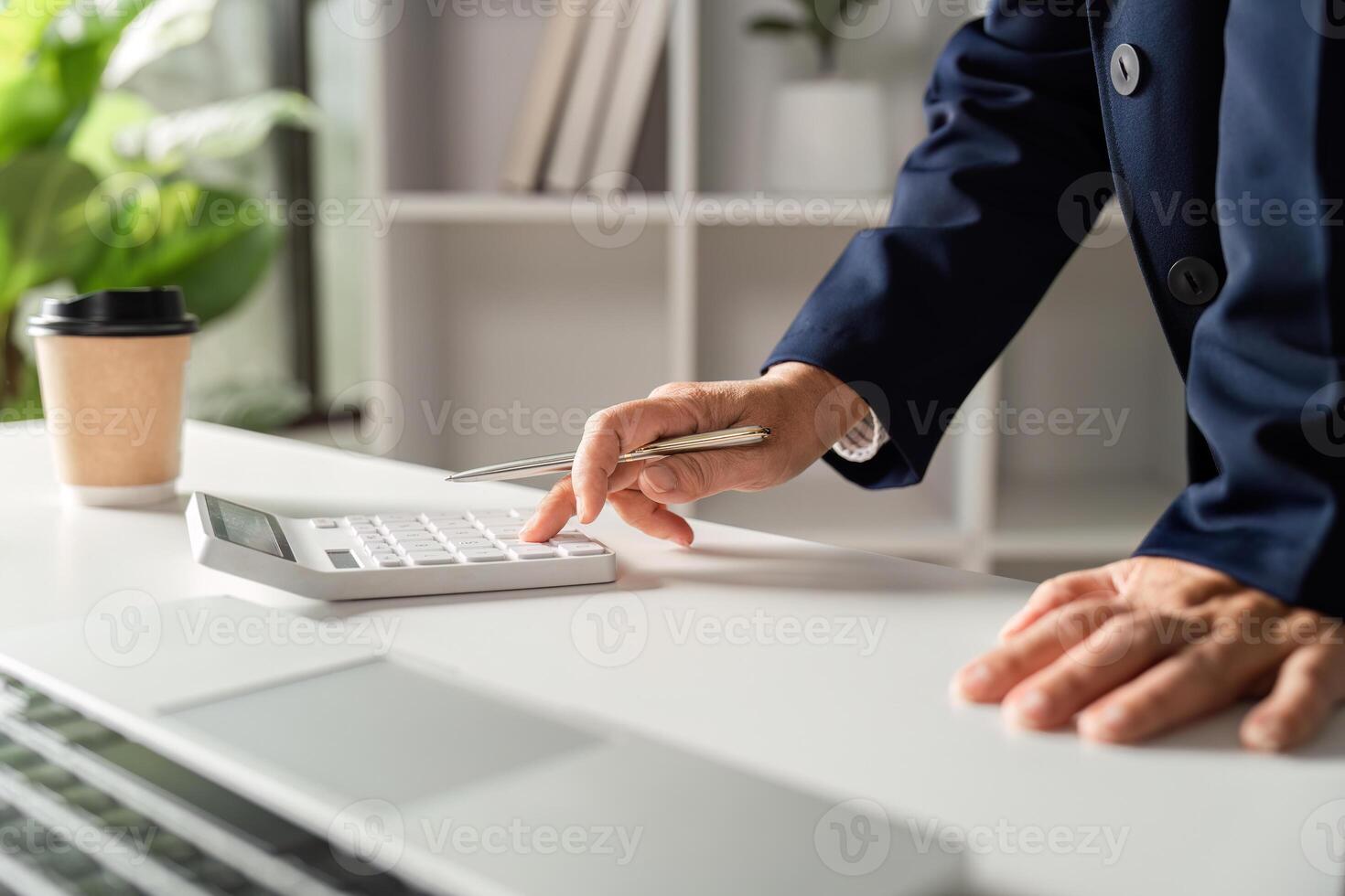 Elderly businesswoman calculating expenses using a calculator in a bright office environment photo