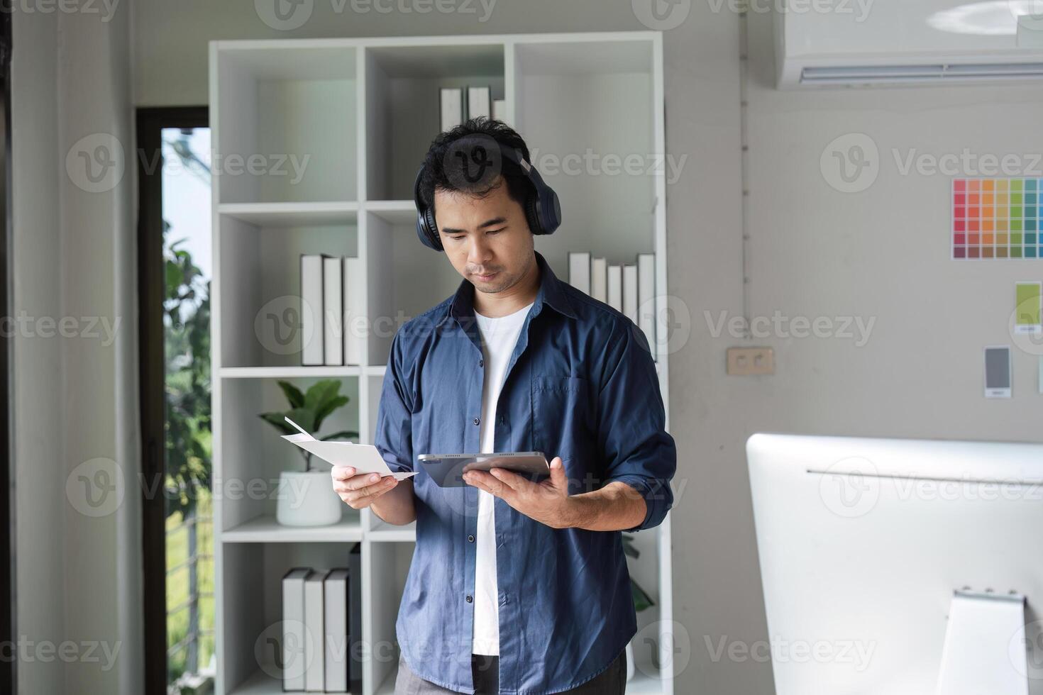 Graphic Designer Analyzing Color Graphs in Modern Office with Digital Tablet and Headphones photo