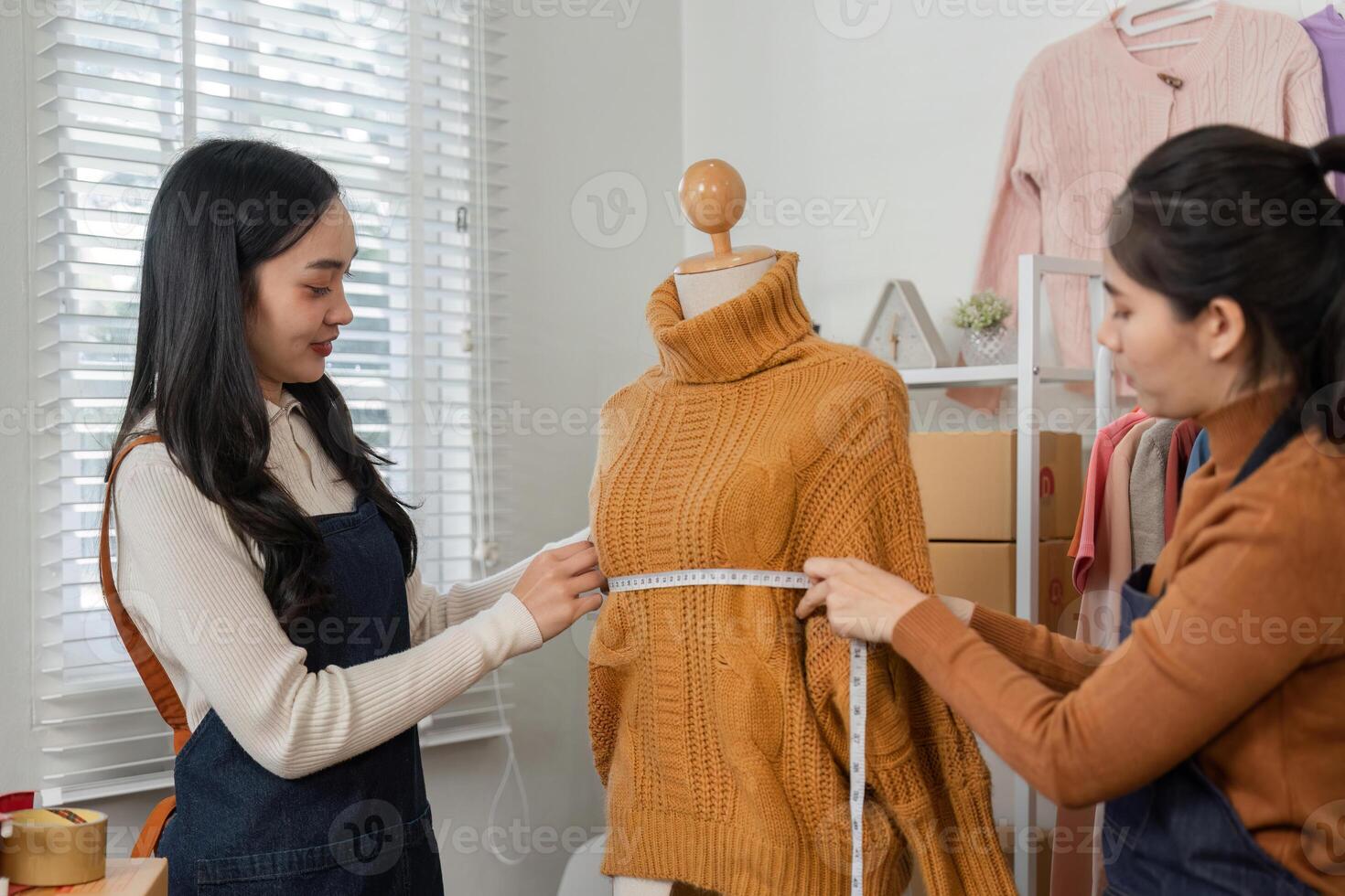 Women tailoring experts measuring a knitted sweater on a mannequin, emphasizing collaboration and precision in fashion design photo