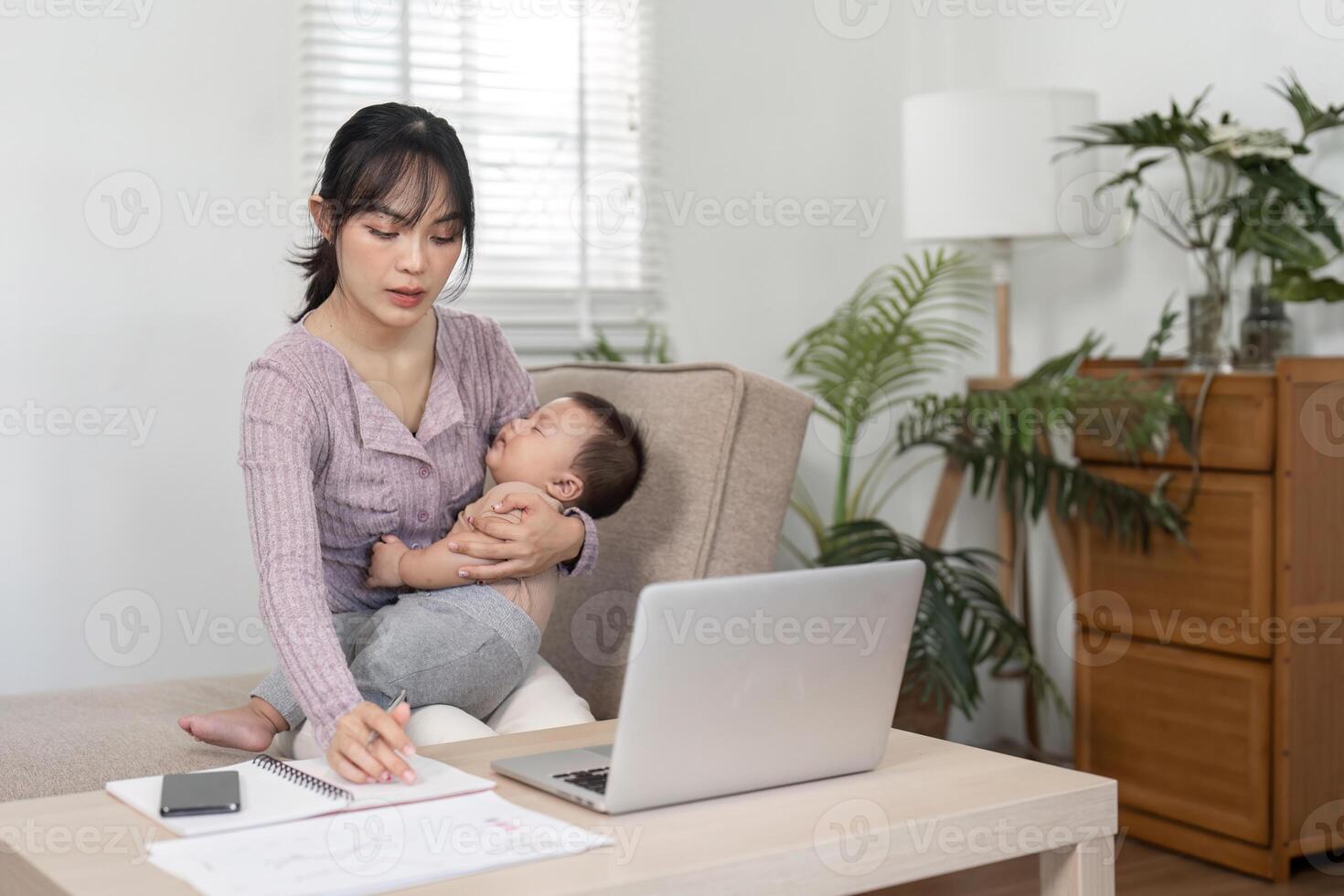 Mother balancing work and parenting while caring for her baby at home office photo