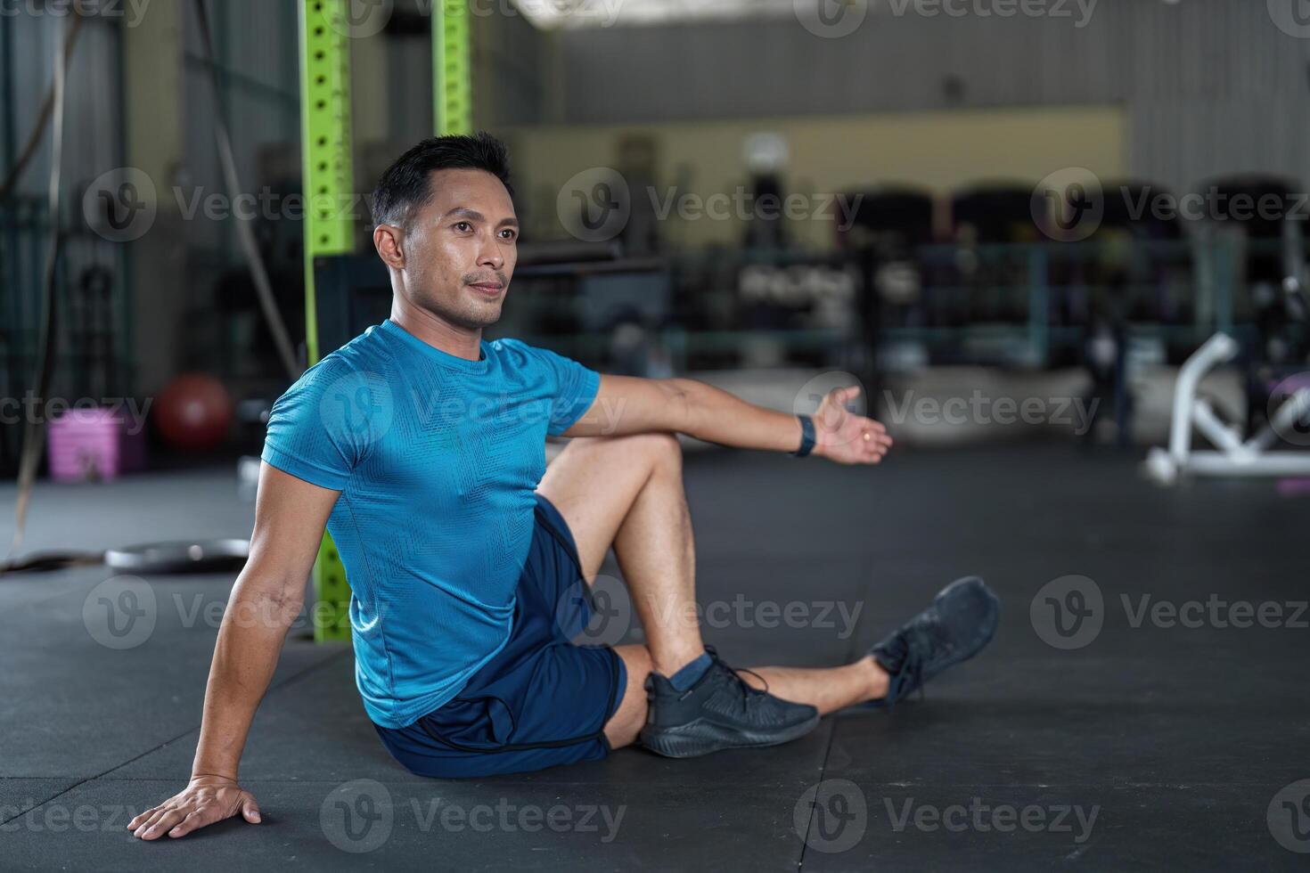 Fitness Stretching Routine. A man performing a seated stretch in a gym environment. photo