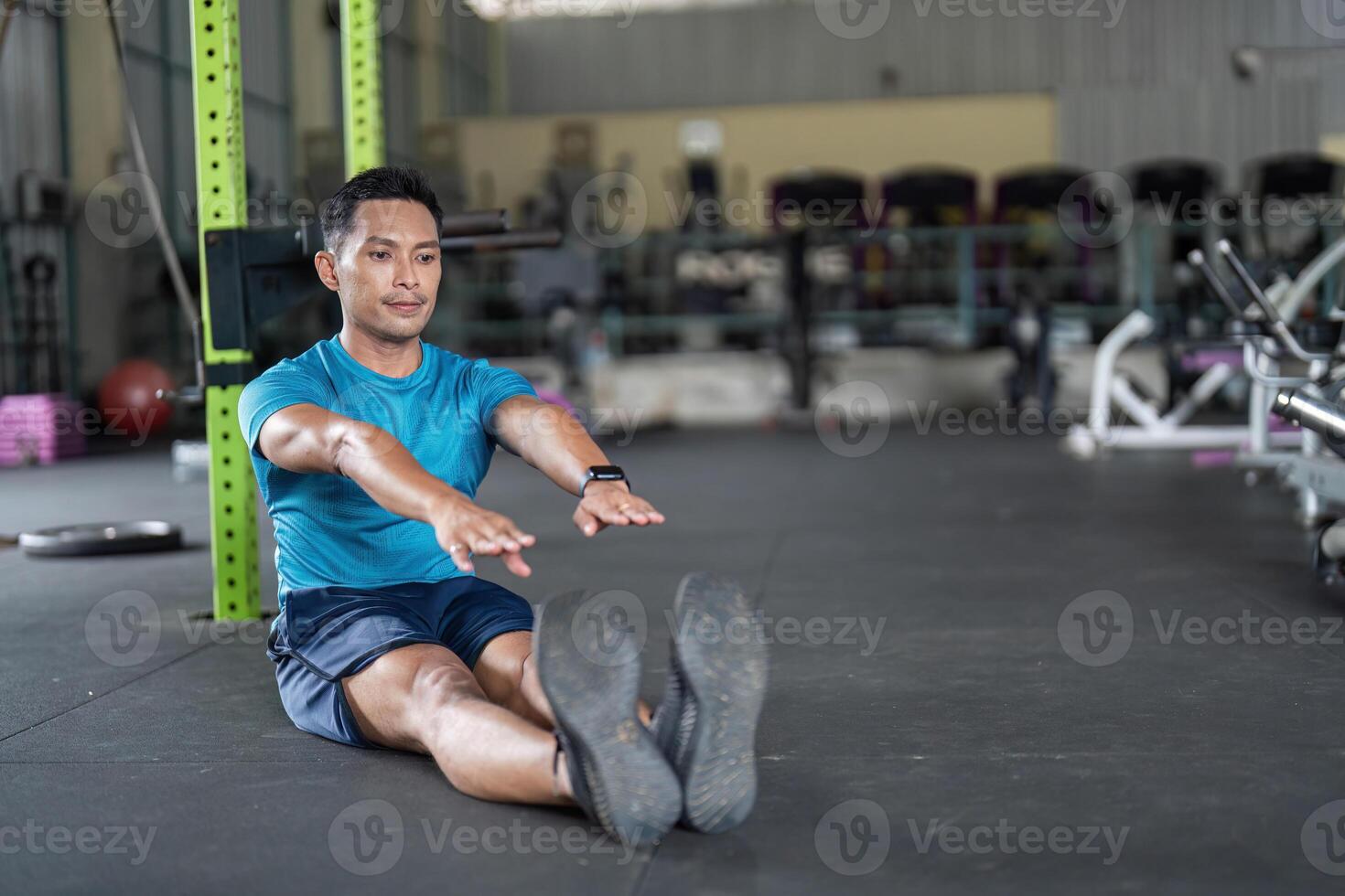 Fitness Focus. Man seated on gym floor, reaching out during a stretching exercise. photo