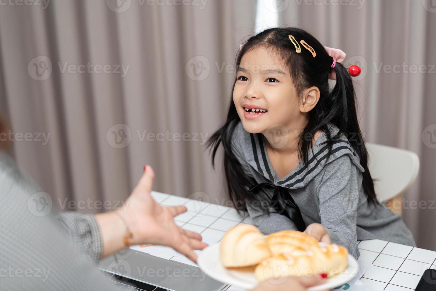 Joyful Moment. Young girl receiving a delicious pastry from her mother at home. photo