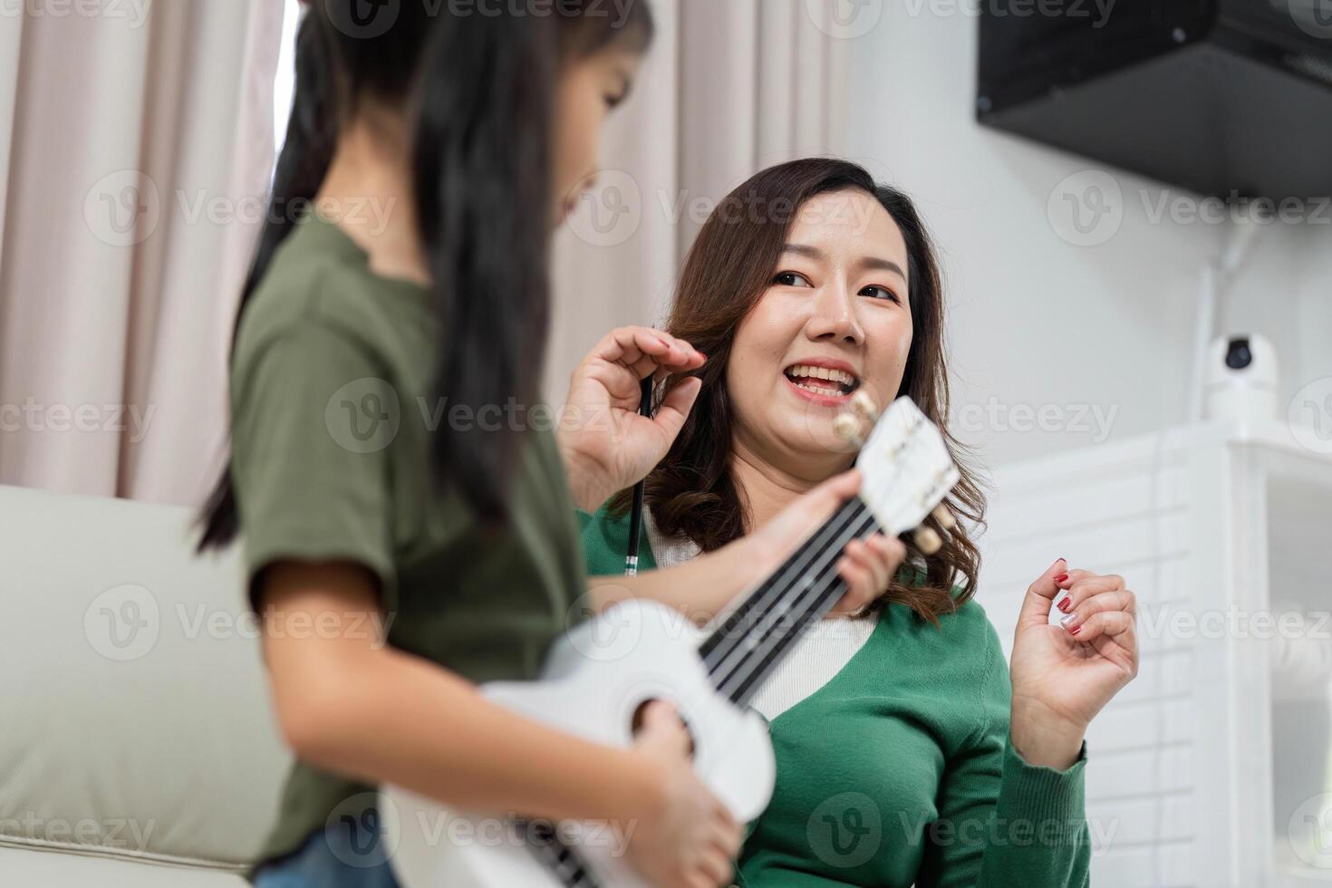 Joyful Music Moments. A mother and daughter share laughter while playing the ukulele. photo
