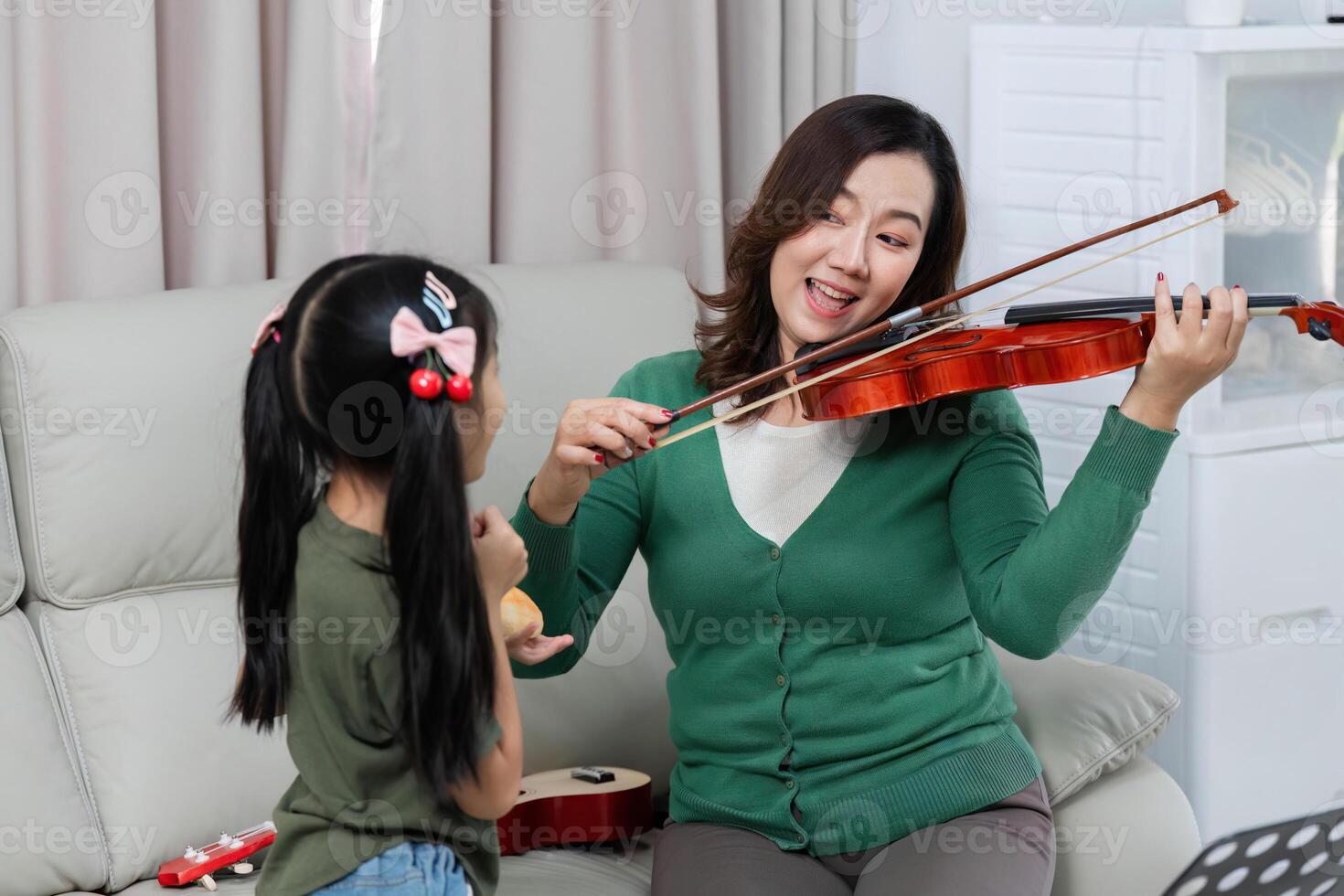 Musical Interaction. Mother and daughter enjoy playing violin together at home. photo