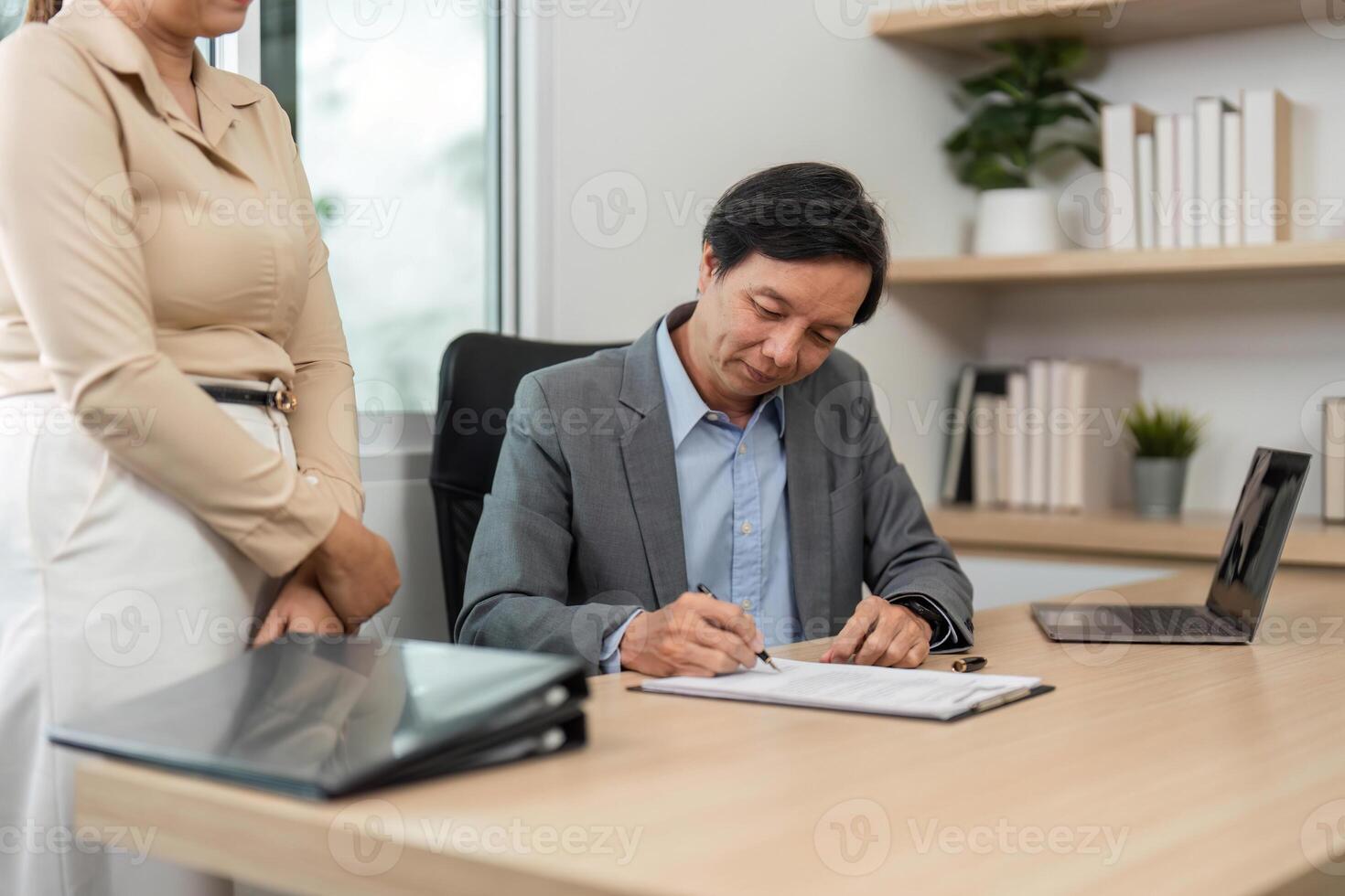 Business Collaboration and Document Signing. Businessman completing paperwork with a colleague in a modern office. photo