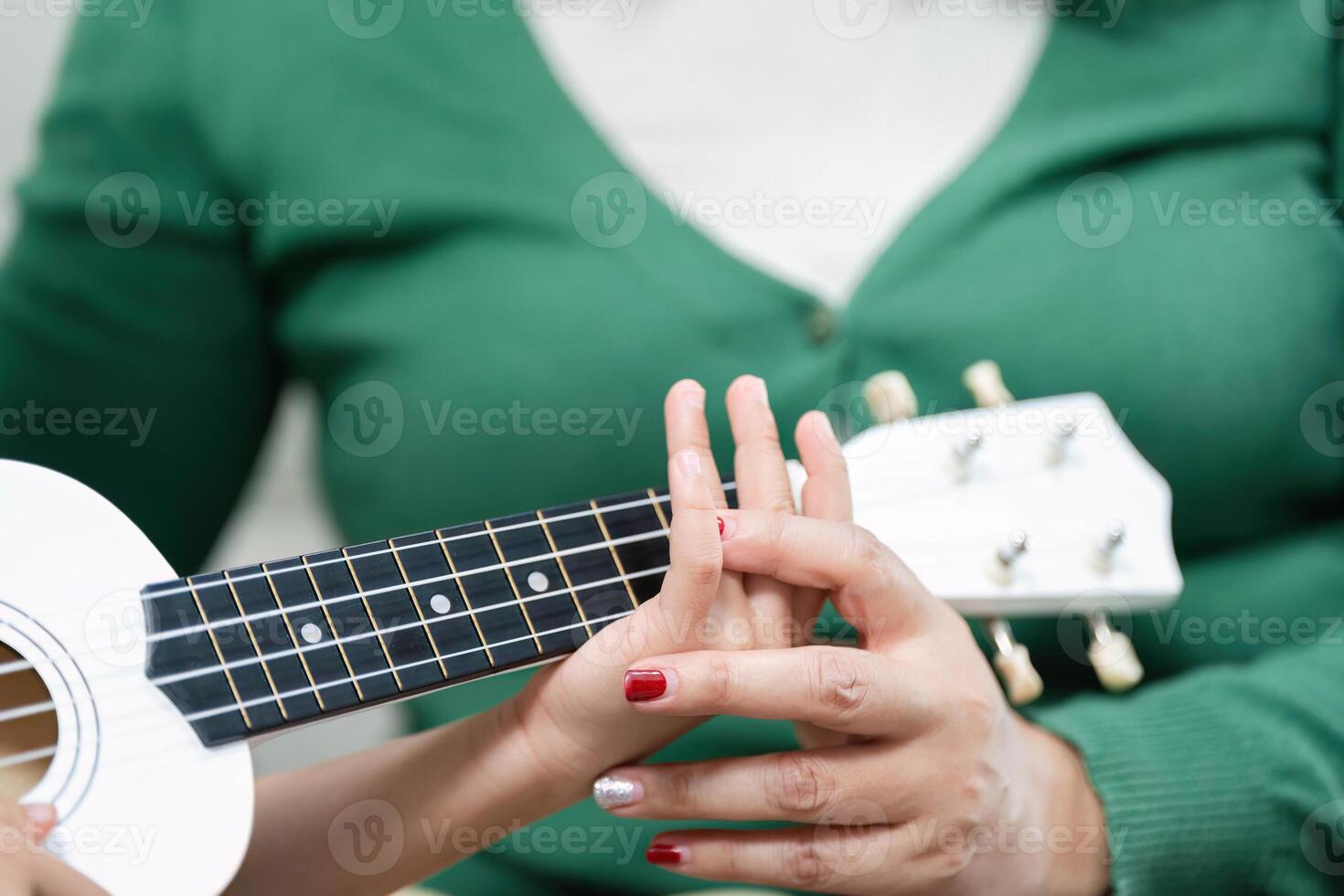 Hands-on Learning. A mother assists her daughter in mastering ukulele techniques. photo