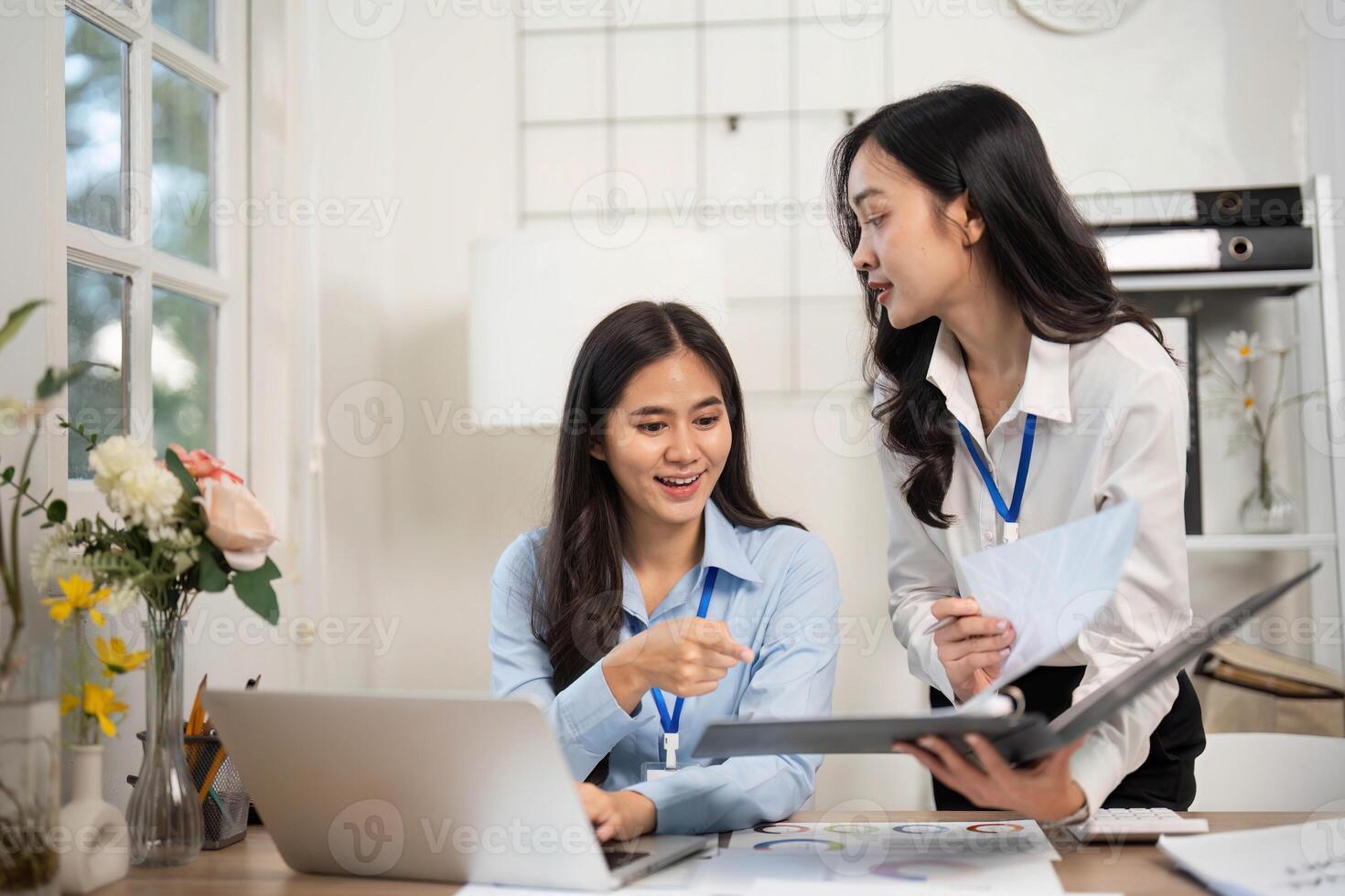 Collaborative Office Environment. Two women discussing project insights at a desk. photo
