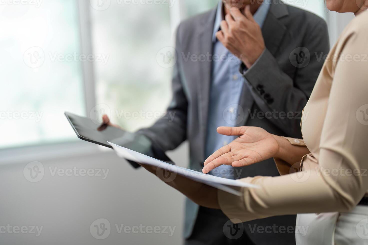 Focused Business Analysis. Colleagues discussing project details with documents and tablet. photo