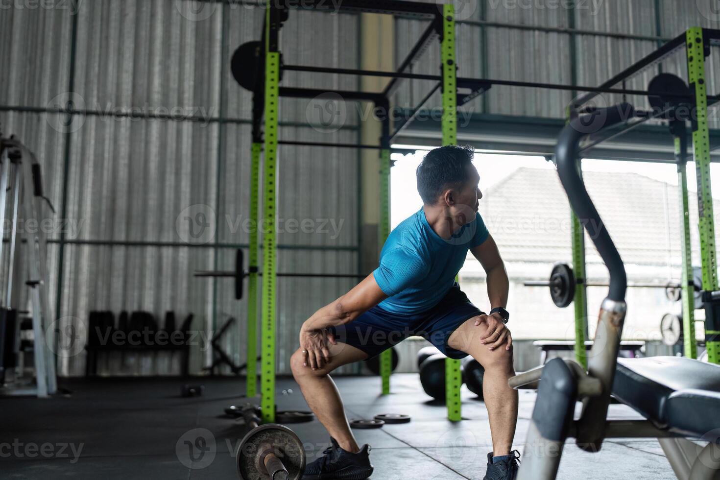 Fitness Workout. Young man performing squats in gym environment. photo
