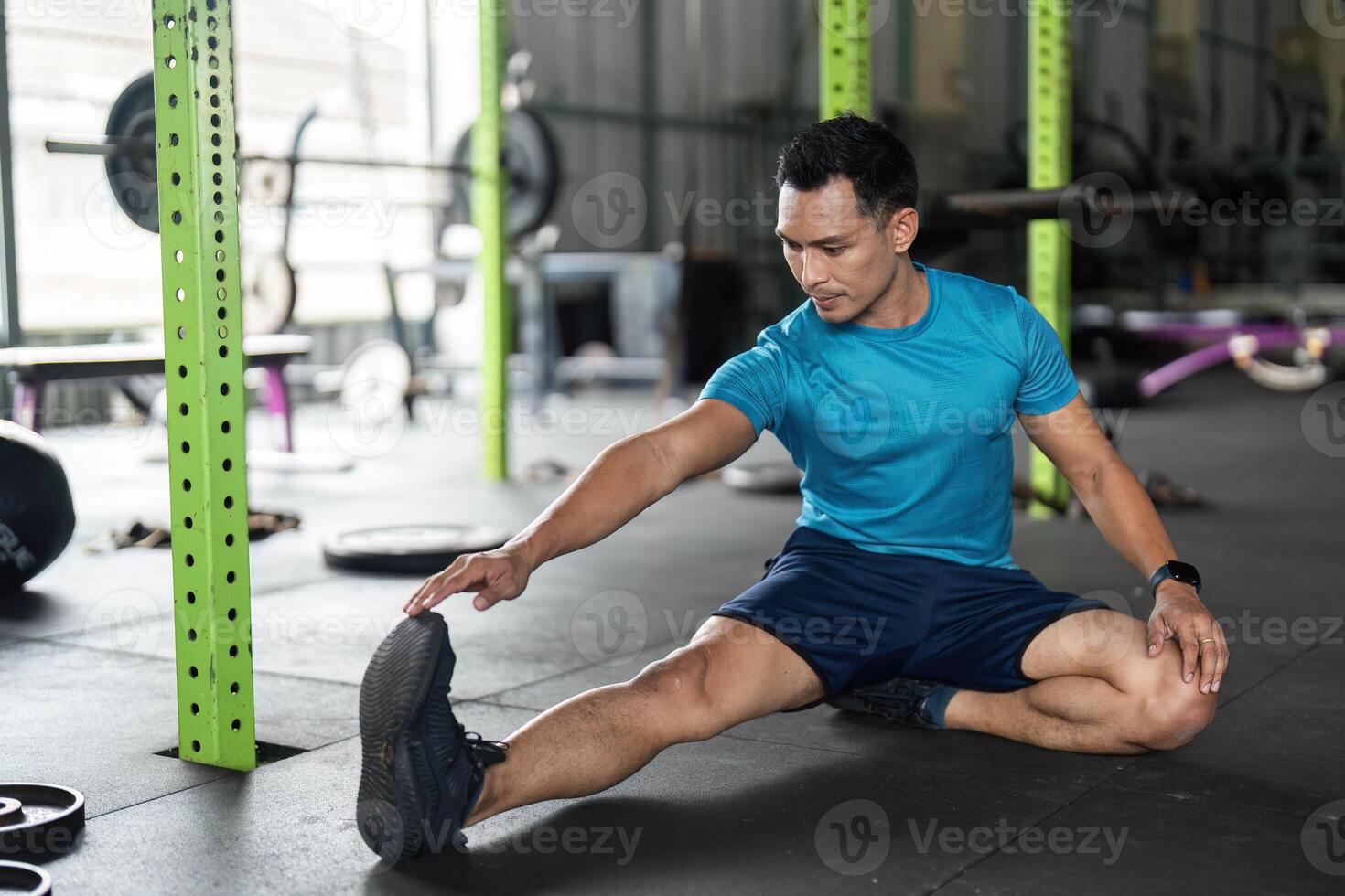 Fitness Stretching Routine. Young man performing a seated stretch exercise in a gym. photo