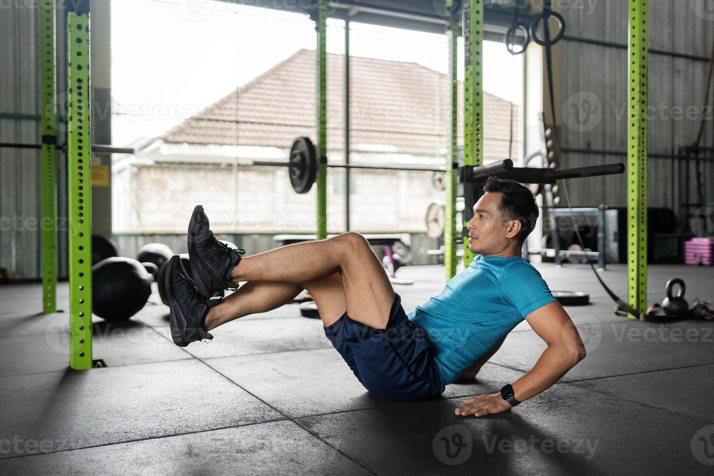 Fitness Core Exercise. Man performing a bicycle crunch in a gym. photo