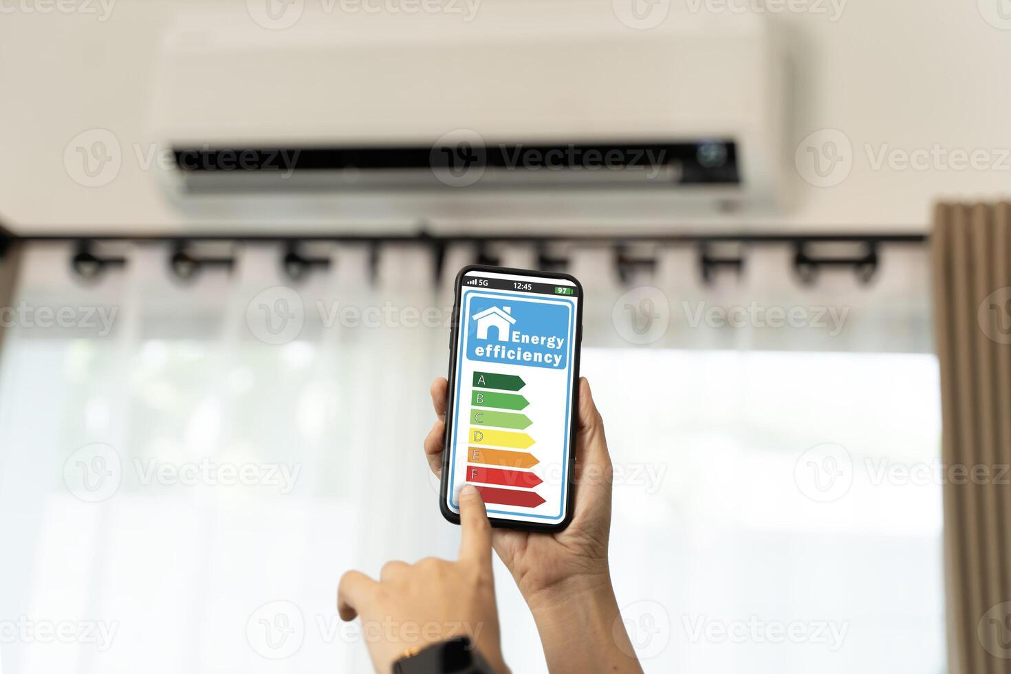 Smartphone displaying energy efficiency rating with air conditioner on background for home energy saving concept photo