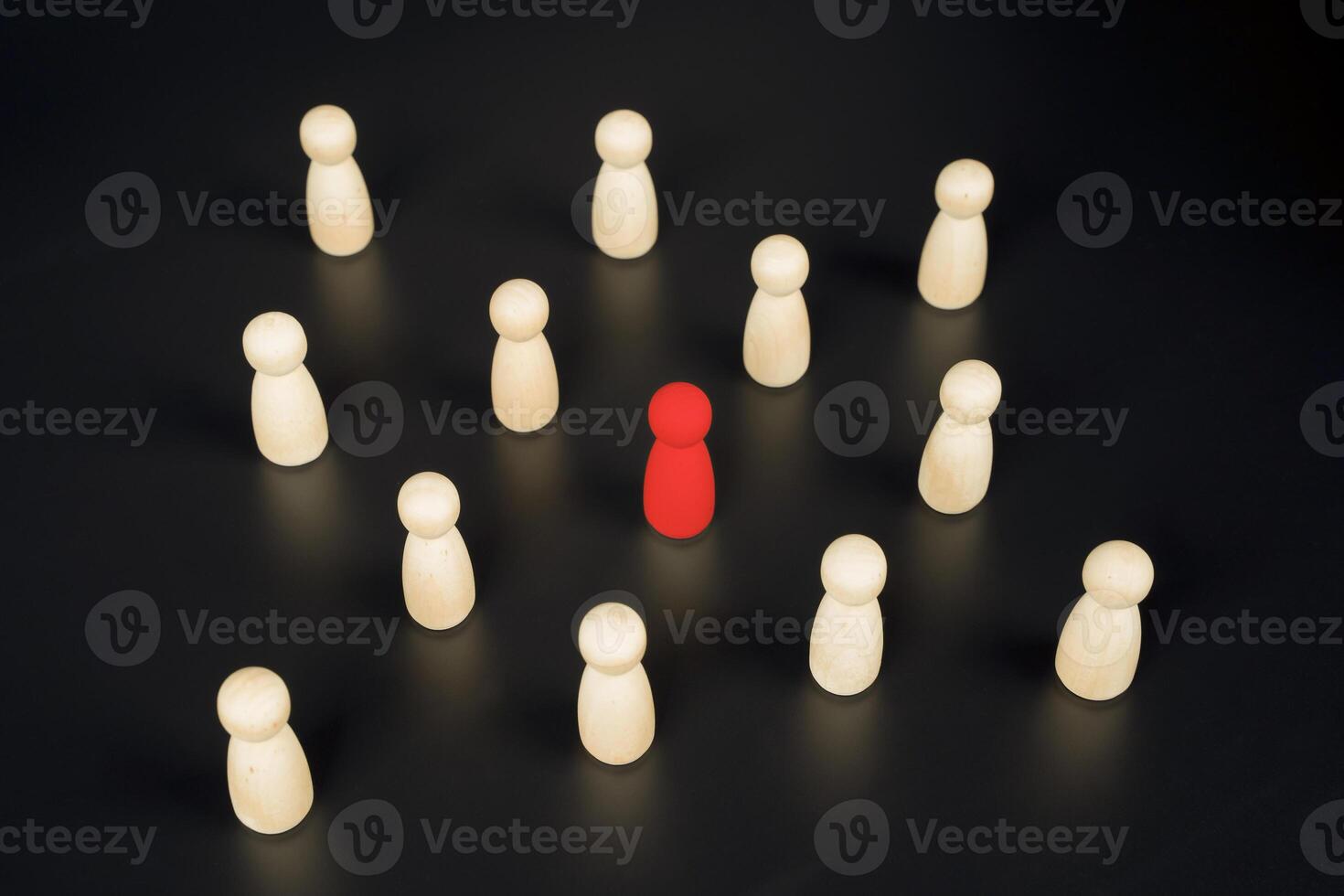 Red pawn surrounded by wooden pawns symbolizing isolation, bullying, discrimination or being different photo