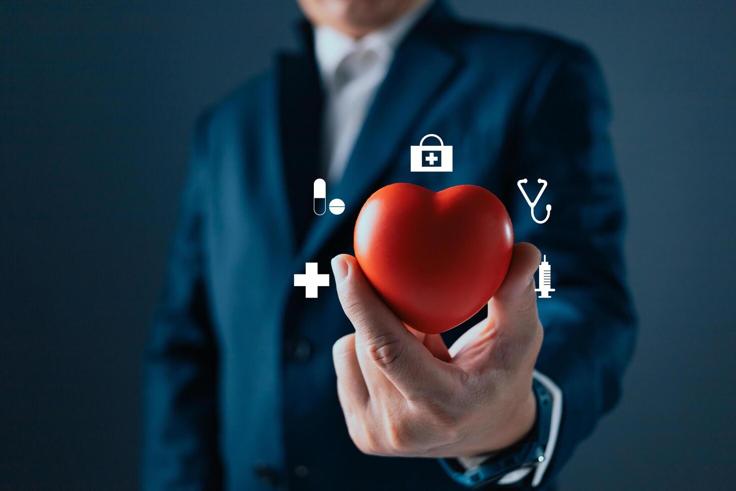 A person in a suit holds a red heart, surrounded by medical icons like a stethoscope, syringe, and cross, symbolizing healthcare, wellness, and the importance of health and medical care. photo