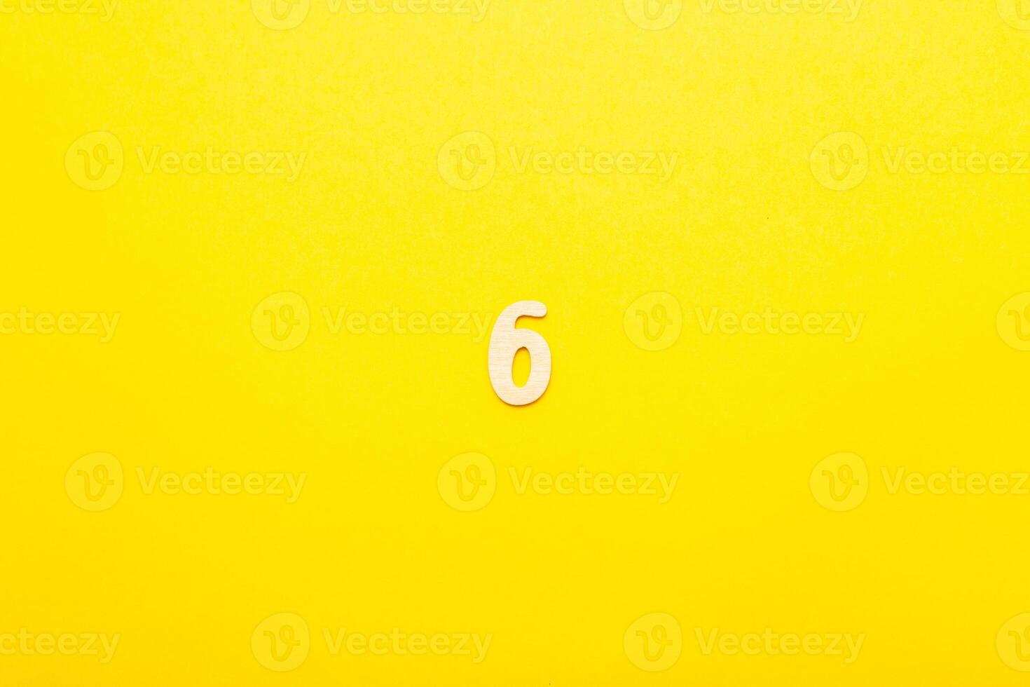Top view of wooden number 6 six on yellow bright background. photo