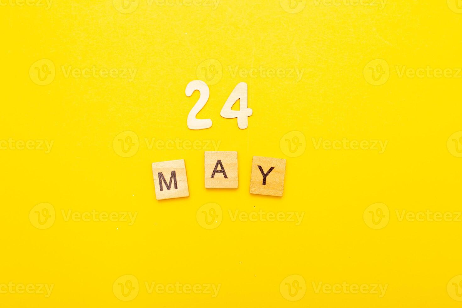 Top view of word 24 May calendar date made by wooden cubes on yellow color background photo
