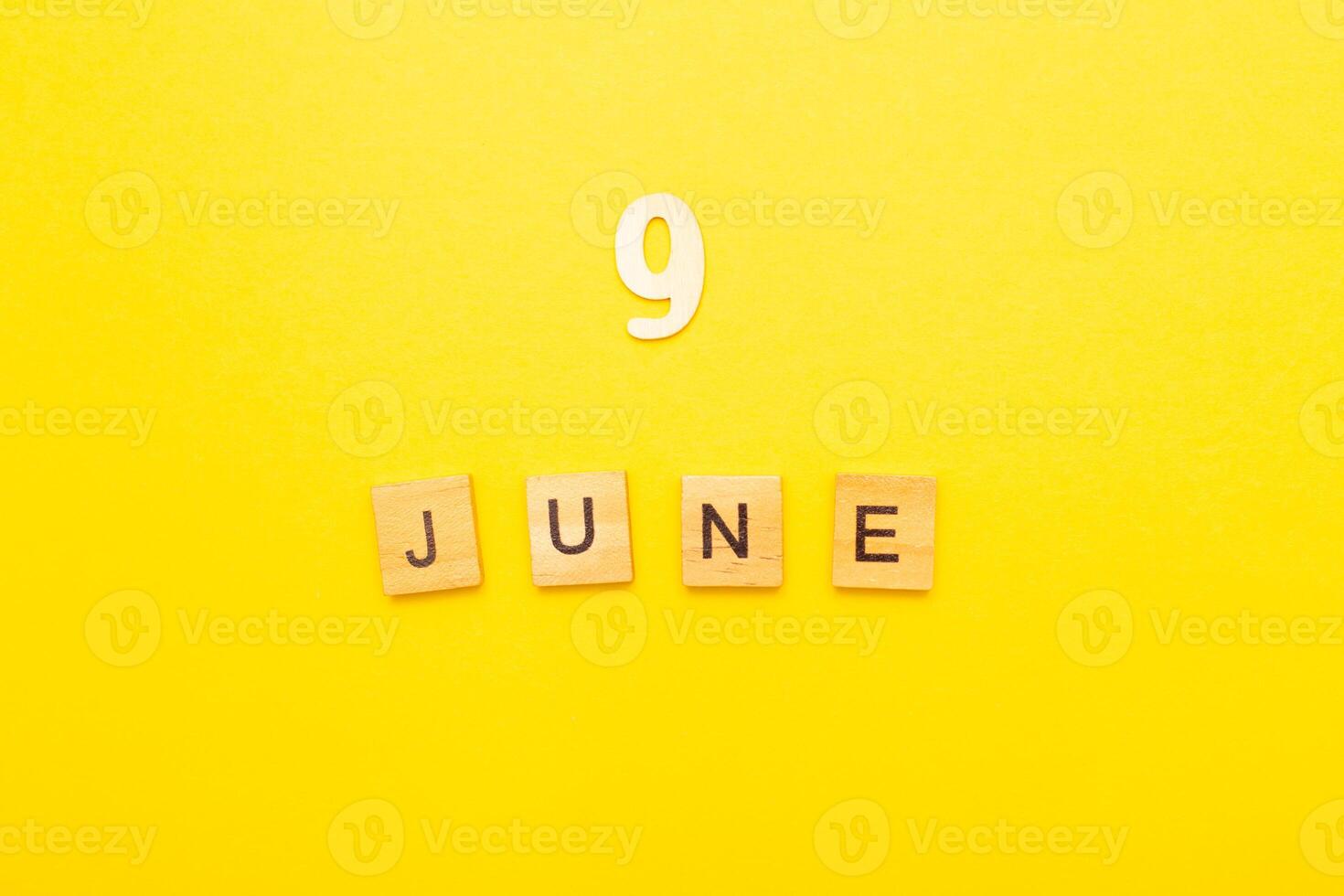 Top view of word 9 June calendar date made by wooden cubes on yellow color background photo