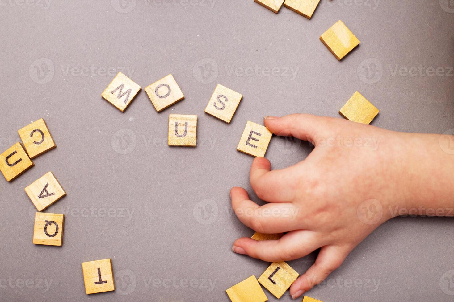 child hand hands collecting word mouse from wooden cubes on gray background photo