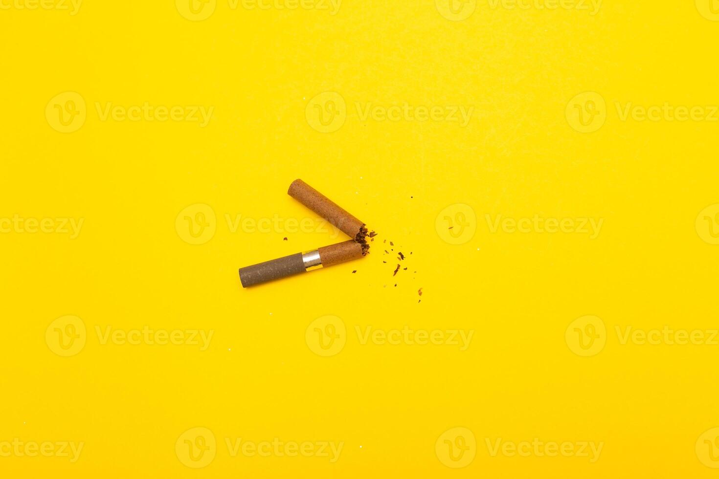 Top view of broken cigarette on a yellow background closeup photo