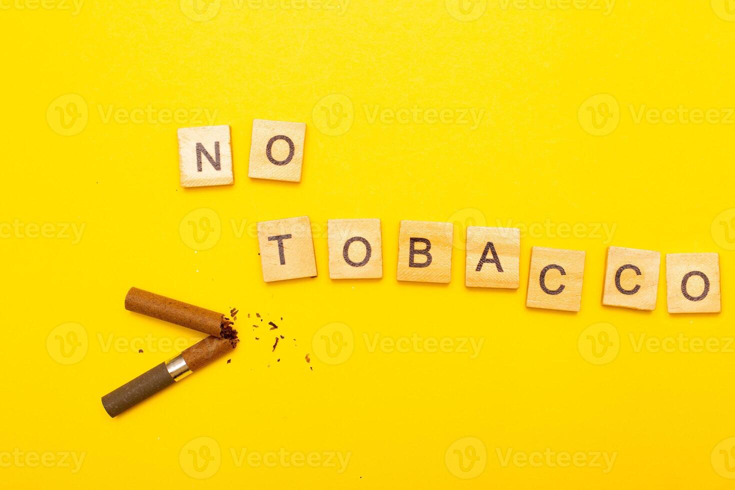 Top view of broken cigarette with the word no tabaco on a yellow background closeup photo