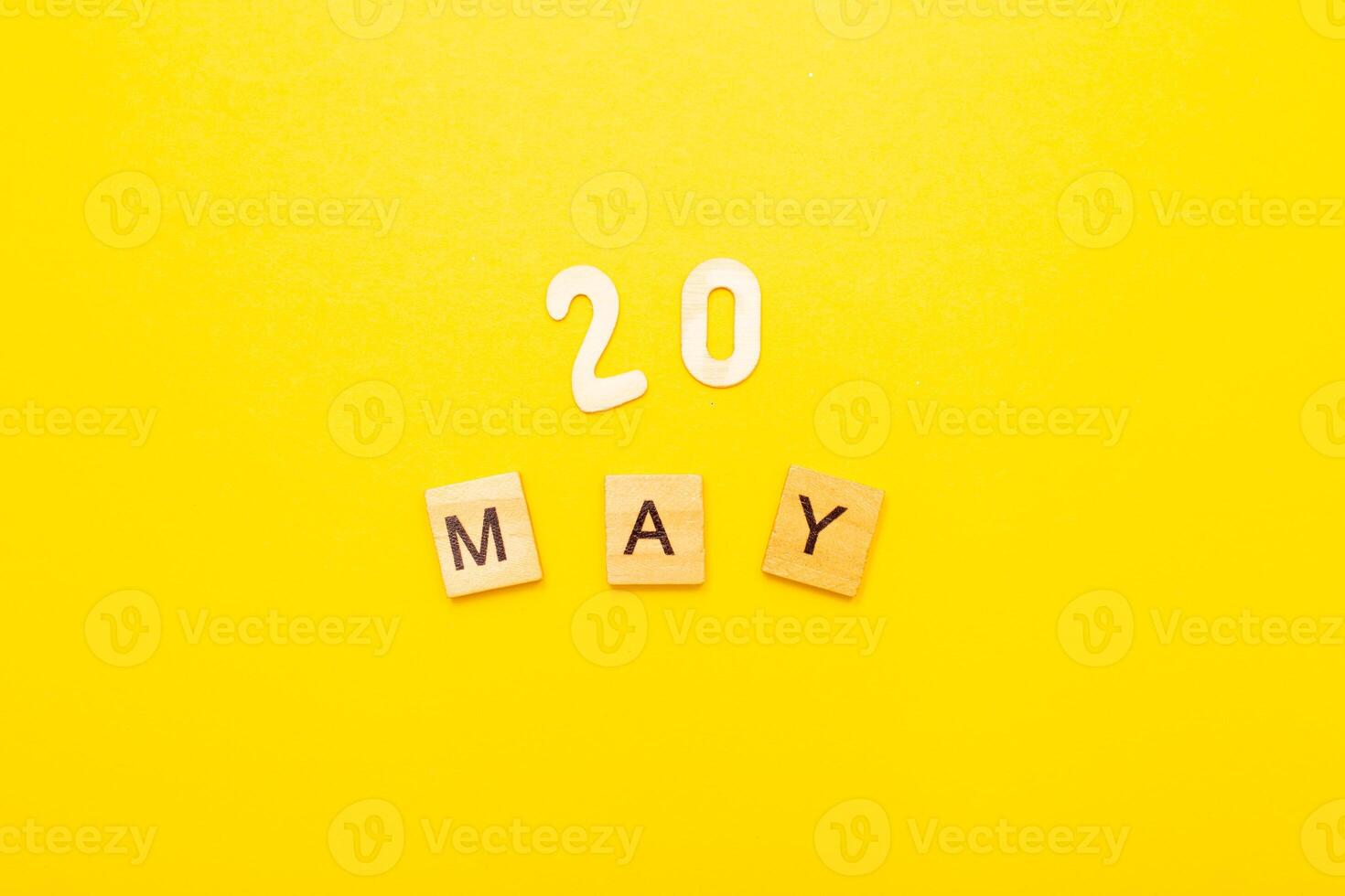 Top view of word 20 May calendar date made by wooden cubes on yellow color background photo