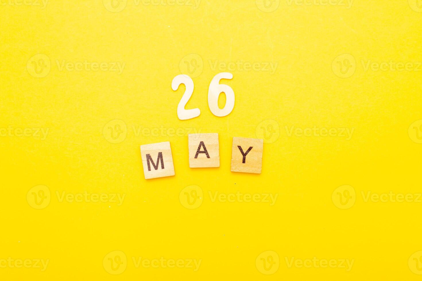 Top view of word 26 May calendar date made by wooden cubes on yellow color background photo