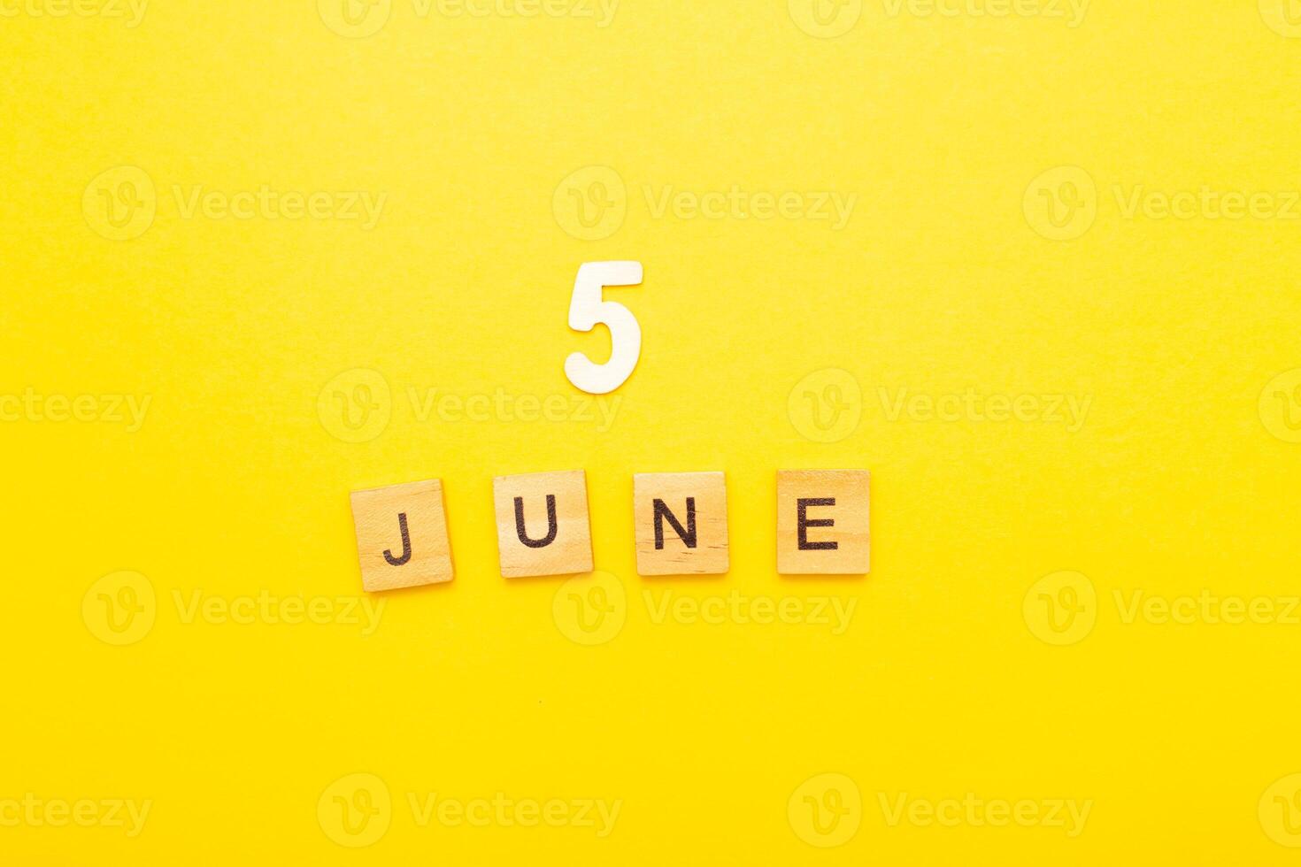 Top view of word 5 June calendar date made by wooden cubes on yellow color background photo
