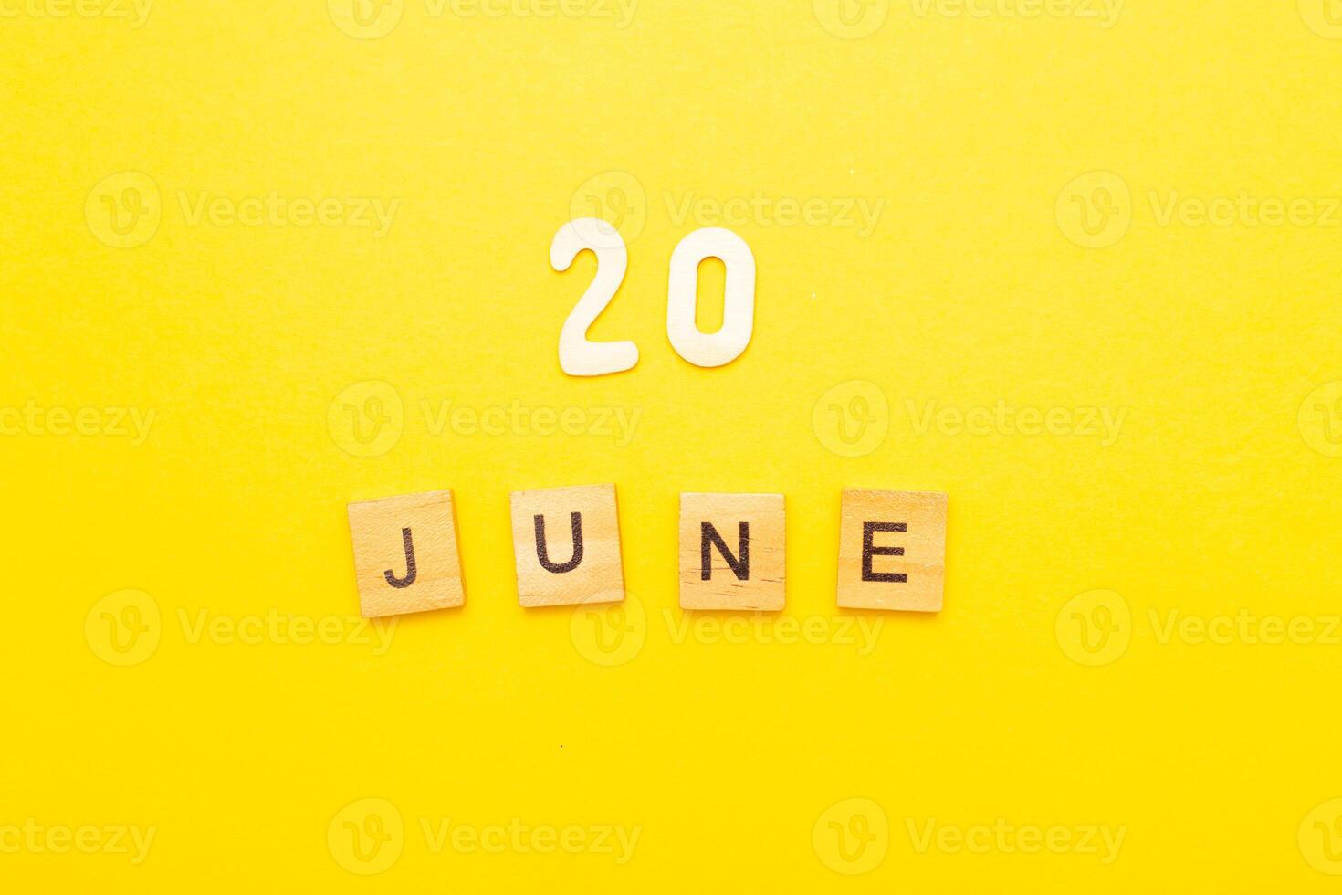 Top view of word 20 June calendar date made by wooden cubes on yellow color background photo