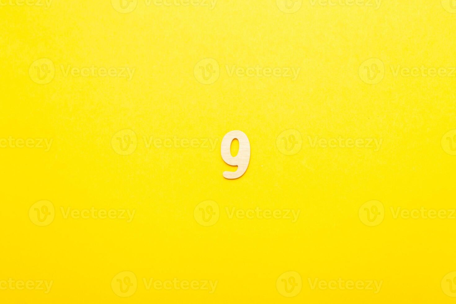 Top view of wooden number 9 nine on yellow bright background. photo