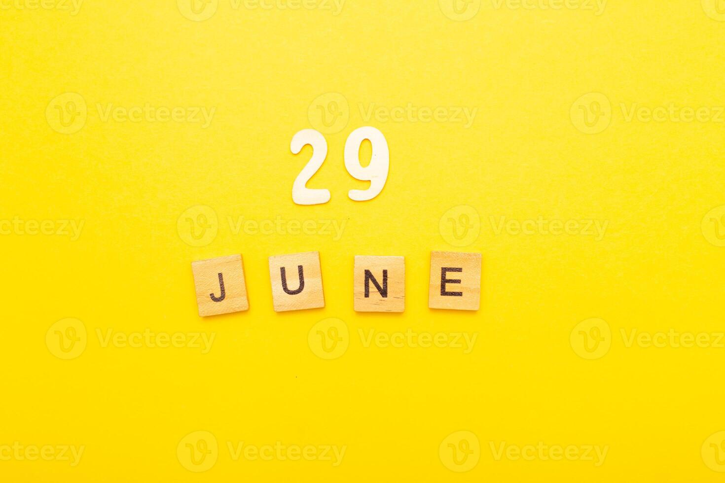 Top view of word 29 June calendar date made by wooden cubes on yellow color background photo