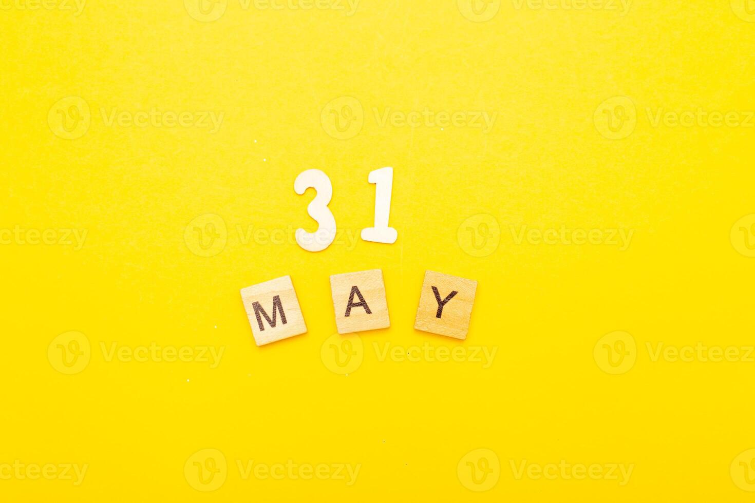 Top view of word 31 May calendar date made by wooden cubes on yellow color background photo