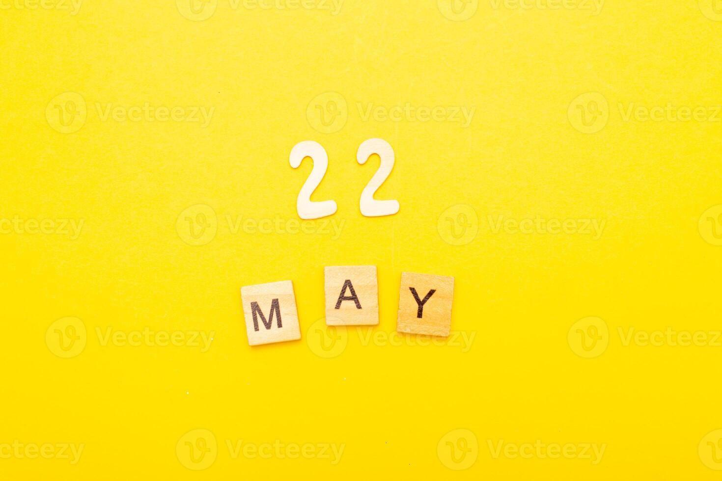 Top view of word 22 May calendar date made by wooden cubes on yellow color background photo