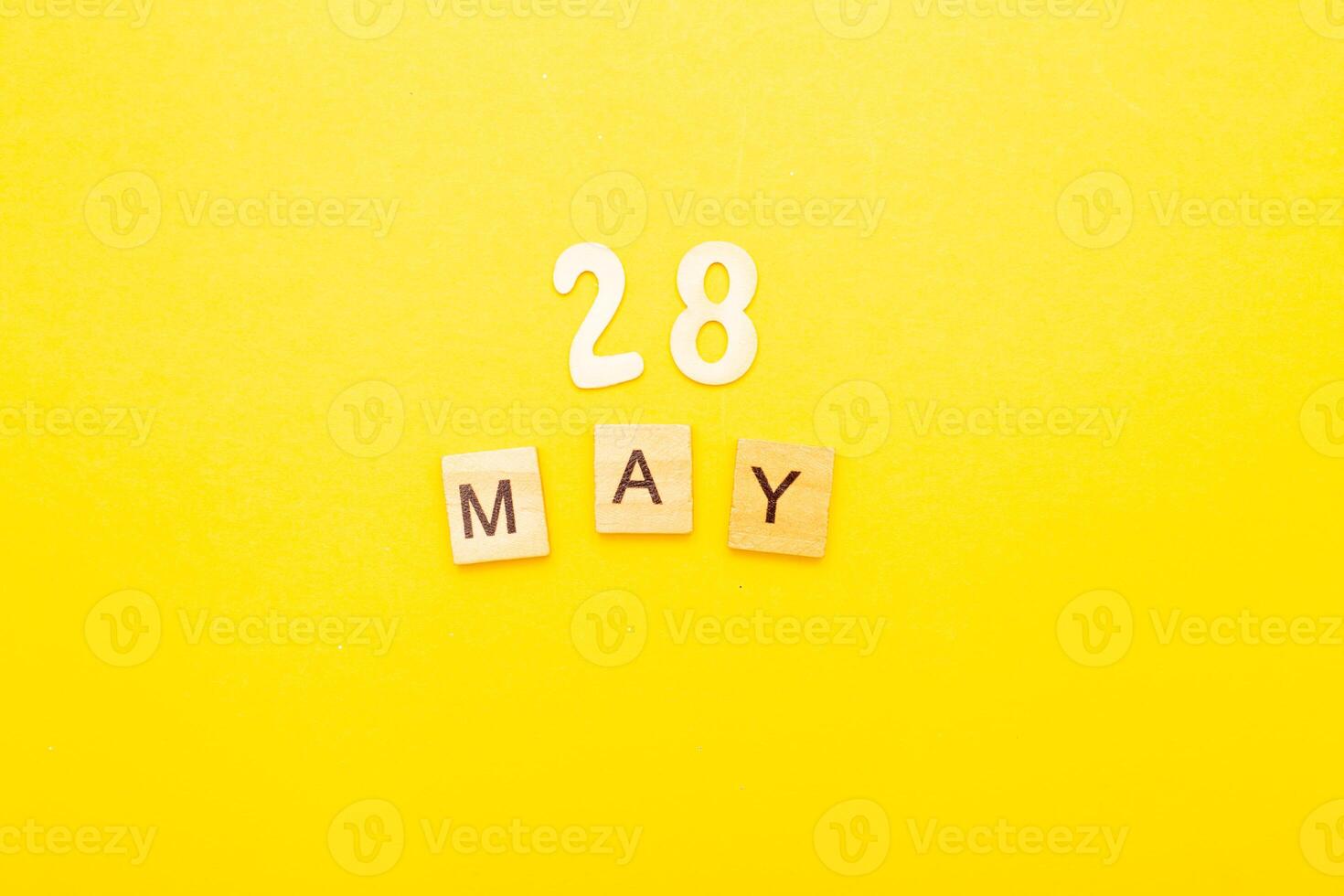 Top view of word 28 May calendar date made by wooden cubes on yellow color background photo