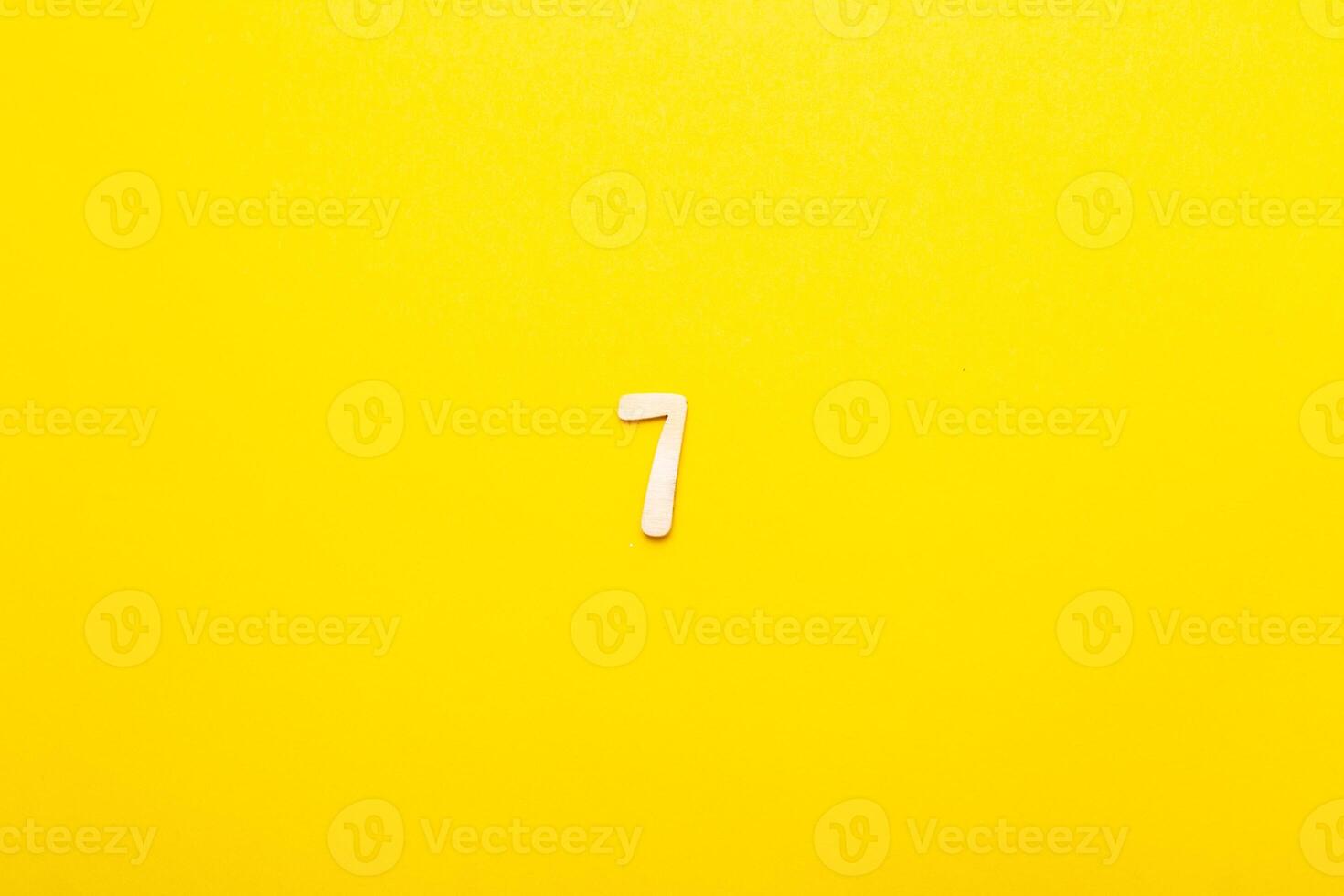 Top view of wooden number 7 seven on yellow bright background. photo